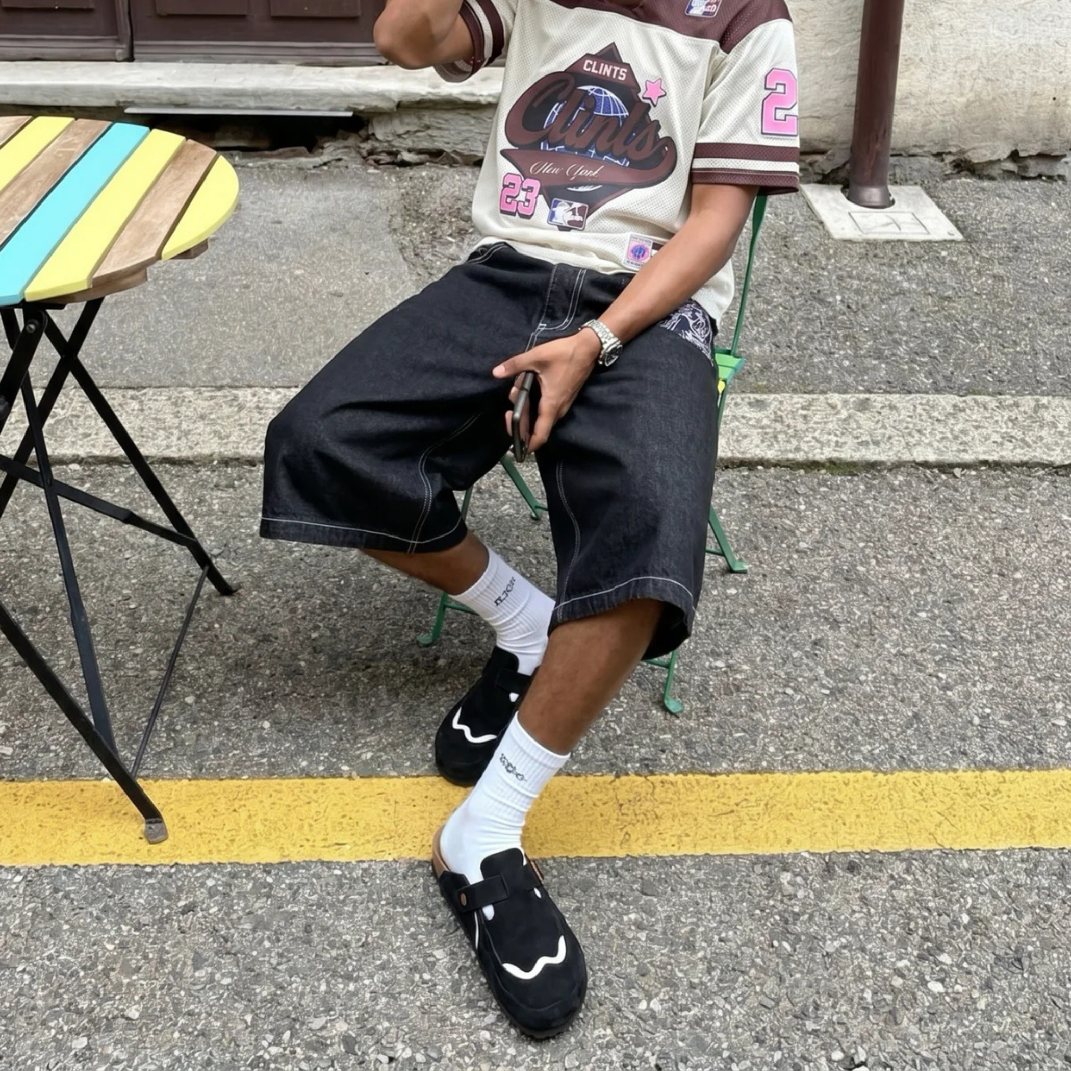 Model wearing Wavey Clogs in black with white socks and black denim shorts