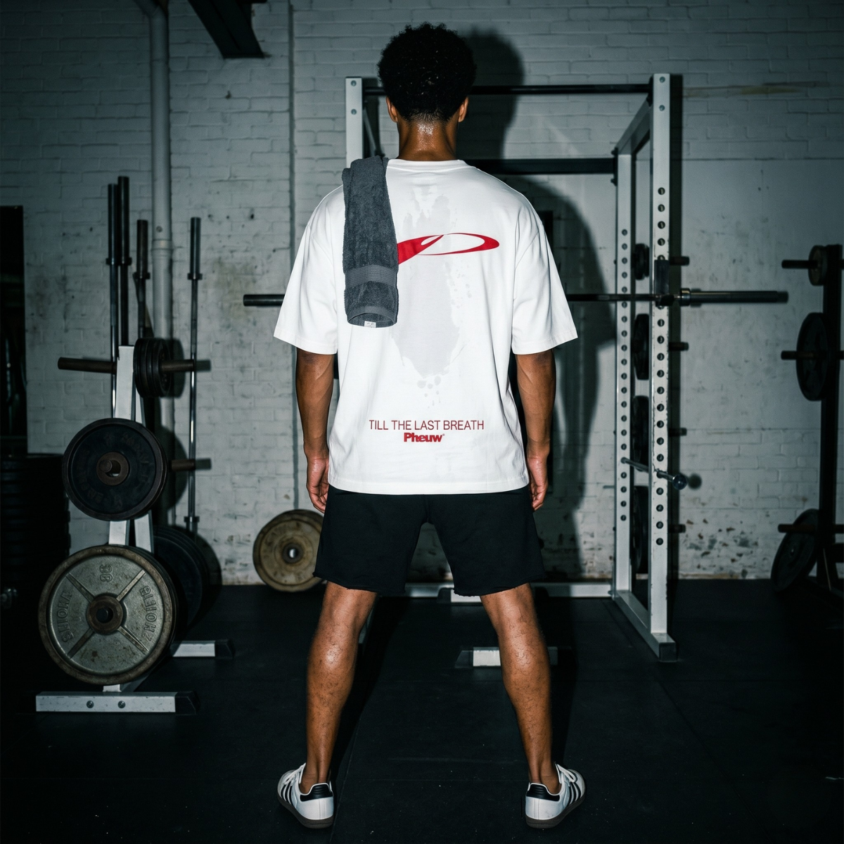 Person wearing a white t-shirt with red graphics in a gym setting